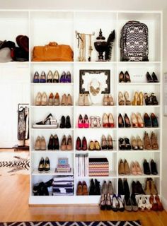 a white shelf filled with lots of shoes and purses on top of wooden floors