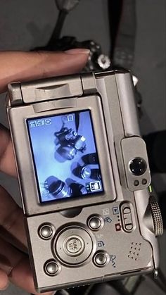 a person holding a silver camera in their left hand and taking a picture with it