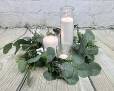 candles and greenery are arranged on a table