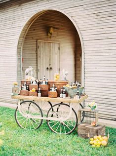 an old fashioned wagon with bottles on it is sitting in front of a barn door