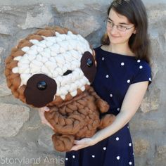 a woman is holding a stuffed sheep made out of knitted yarn and wool balls