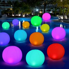 colorful balls sitting in the middle of a pool at night