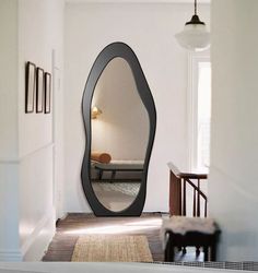 a large mirror in the middle of a hallway next to a chair and table with a lamp on it