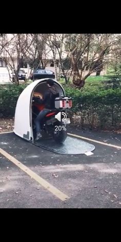 a man riding on the back of a motorcycle in a parking lot next to trees