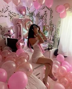 a woman sitting on top of a bed surrounded by balloons