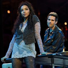 a man and woman standing next to each other in front of a piano on stage