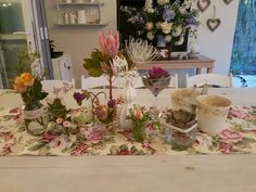 a table topped with lots of flowers and vases