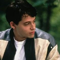 a young man wearing a leather jacket and white t - shirt looks off into the distance