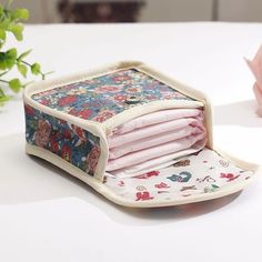 an open wallet sitting on top of a table next to a pink flower potted plant