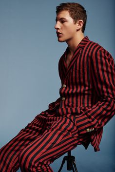 a man sitting on top of a chair wearing a red and black striped shirt dress