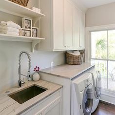 a washer and dryer in a white laundry room with open shelving on the wall