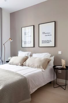 a white bed sitting in a bedroom next to two framed pictures on the wall above it