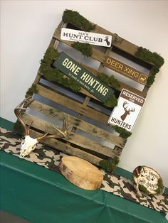 a wooden crate with moss growing on it and deer heads mounted to the side, sitting on a green table cloth