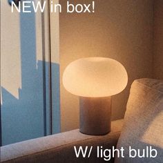 a light bulb sitting on top of a table next to a couch and window with the words, new in box w light bulb