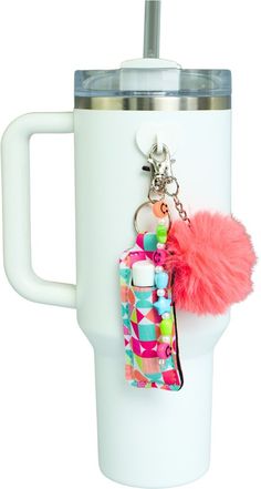 a white cup with a pink pom - pom keychain attached to it