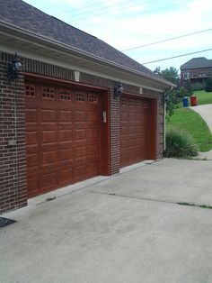 two brown garage doors on the side of a brick building