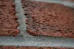 a close up view of the side of a brick wall with small cracks in it