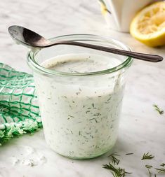 a glass jar filled with yogurt next to a lemon slice and green napkin