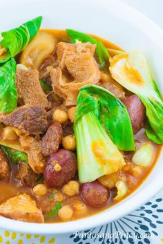 a white bowl filled with meat, beans and veggies on top of a table