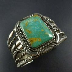 "VINTAGE NAVAJO BRACELET DESCRIPTION: This impressive cuff features a rectangular specimen of Ajax Mine turquoise, light blue-green with golden brown matrix. The gemstone is secure in smooth bezel, on a foundation of heavy gauge vintage sterling silver. Thick twisted silver rope alternates between the chisel stamped and hand-stamped features of the cuff. This bracelet will be a cherished addition to your collection of fine vintage Native American jewelry. MEASUREMENTS: Interior of the cuff measu Antique Turquoise Bangle Cuff Bracelet, Luxury Green Rectangular Bracelets, Turquoise Bangle Cuff Bracelet For Formal Occasions, Elegant Turquoise Cuff Bracelet, Elegant Turquoise Bracelet With Patina, Elegant Turquoise Bracelets With Patina, Classic Rectangular Cuff Bracelet Gift, Antique Turquoise Cuff Bracelet Gift, Antique Turquoise Cuff Bracelet As Gift