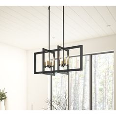 a chandelier hanging from the ceiling in a dining room with windows overlooking trees