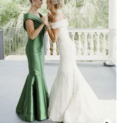 two beautiful women in green dresses standing next to each other on a porch with palm trees