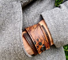 "I've made this wrapping cuff out of soft, scuffy brown and sienna brown leather. The leather has been hand printed with a design using indelible ink. Machine stitched, it has an attached elastic that hooks over a button, so this cuff will adjust to fit most wrist sizes 5.75\" to 7\" in circumference OR choose a custom size. At the narrowest, the width of the cuff is 1.25\" and at the widest it's 2\". Only premium quality leather and supplies are used to handcraft each item. Every item shipped i Wrap Armband, Leather Jewellery, Brown Leather Bracelet, Upcycled Leather, Floral Bracelet, Multi Strand Bracelet, Leather Cuffs Bracelet, Leather Gifts, Leather Wrap Bracelet