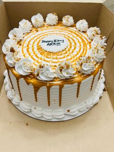 a birthday cake with white frosting and caramel drizzle on top in a box