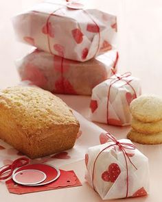 some cookies wrapped in red and white paper next to two bags with hearts on them