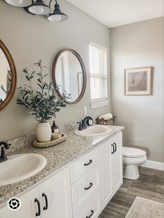 a bathroom with two sinks and mirrors on the wall next to a toilet in it