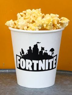 a white bucket filled with popcorn sitting on top of a table next to a yellow wall