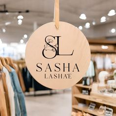 a sign hanging from the side of a store's clothing rack that says, sl & sasha lashase