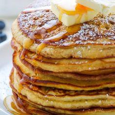 a stack of pancakes with butter and blueberries on the side, ready to be eaten