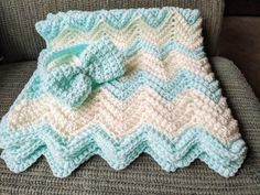 a crocheted blanket with a bow on it is sitting on a gray chair