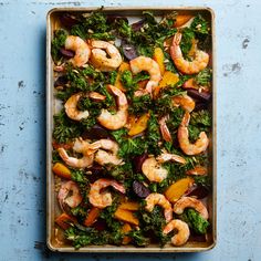 a pan filled with shrimp, broccoli and carrots on top of a blue surface