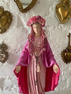 a statue of a woman wearing a pink dress and headdress in front of some heart shaped mirrors