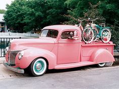 an old pink truck with bicycles on the back