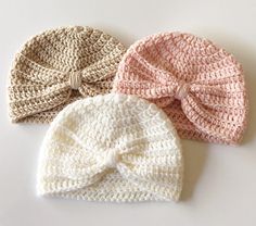 three crocheted hats with bows on them