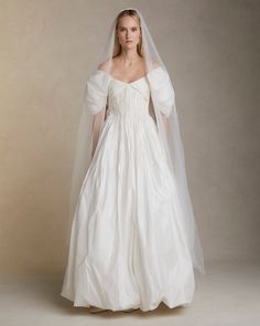 a woman in a white wedding dress with a veil on her head and one arm over her shoulder