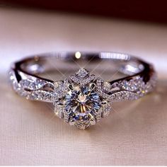 a diamond ring is sitting on top of a white cloth with the center stone surrounded by smaller diamonds