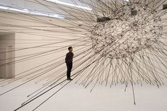 a man standing in front of a large sculpture with many lines on it's face