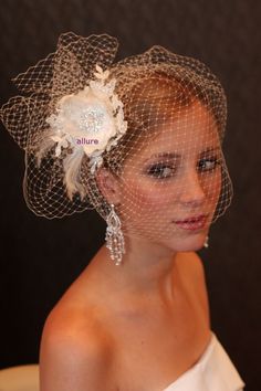 a woman in a white dress wearing a veil with flowers on the side and hair comb