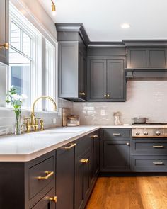 a kitchen with dark gray cabinets and white counter tops, gold pulls on the handles