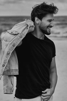 black and white photograph of a man holding a jacket over his shoulder on the beach