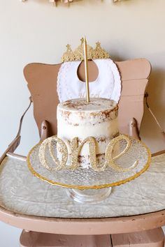 a cake sitting on top of a wooden table next to a white and gold sign