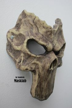 a wooden mask hanging on the wall with a diamond in it's eye hole