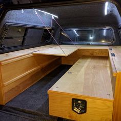 the inside of an empty vehicle with wooden benches and storage area in the back ground