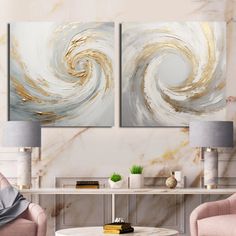 two large paintings on the wall in a living room with chairs and a coffee table