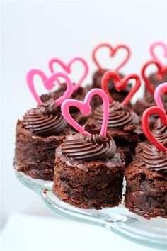 chocolate cupcakes decorated with hearts on a glass platter for valentine's day