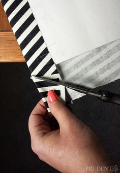 someone cutting fabric with scissors on top of a piece of white and black striped material